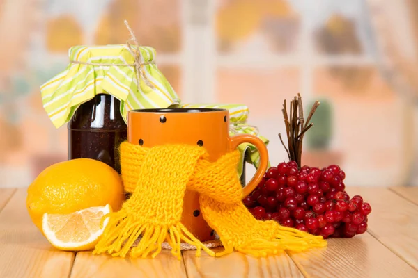 Warming tea from a viburnum, jars with jam and lemon, on a table — Stock Photo, Image