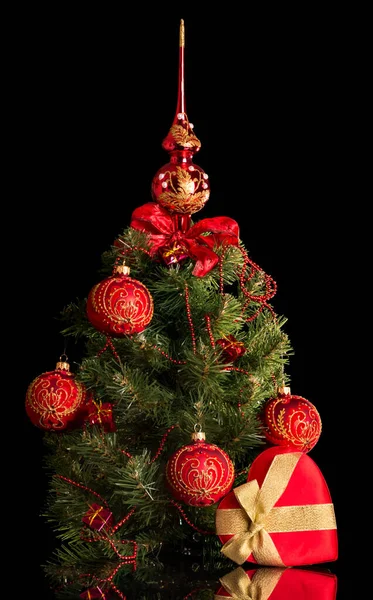 小さなエレガントなクリスマスツリーには、黒い上に隔離された心の横にあるボールやビーズで飾られています。 — ストック写真