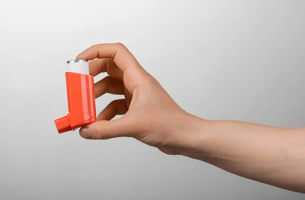 Small portable inhaler in female hand on gray — Stockfoto