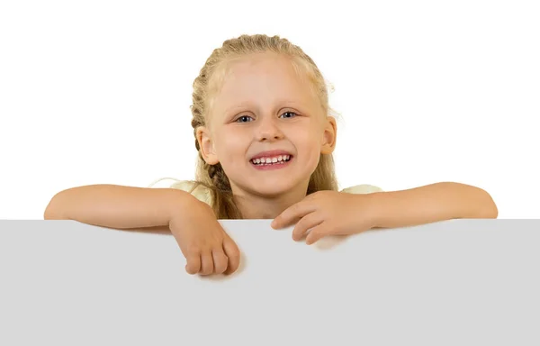 Cute little girl stands behind large poster, isolated on white — ストック写真
