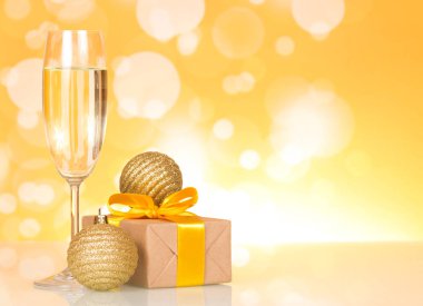 Glass of champagne, Christmas toys and gift, on yellow