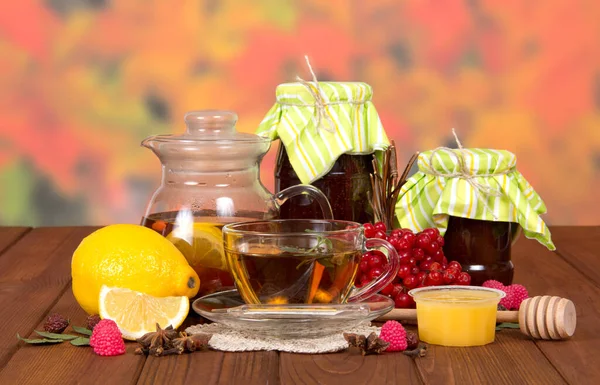 Hot tea, jars of jam, lemon and honey from colds, on table — Stockfoto