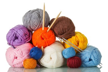 Skeins of yarn of different colors, shapes, quality, and two pairs of knitting needles isolated on white