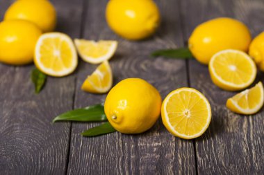 Whole lemon and half in foreground, then lot of citrus, on gray surface
