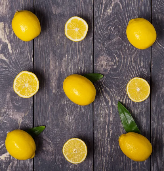 Ganze gelbe Zitronen wechseln sich mit Fruchthälften auf grauer Oberfläche ab — Stockfoto