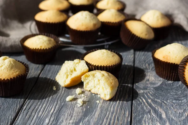 Lot of fresh rosy cupcakes in molds spread out on gray surface — Stock Photo, Image