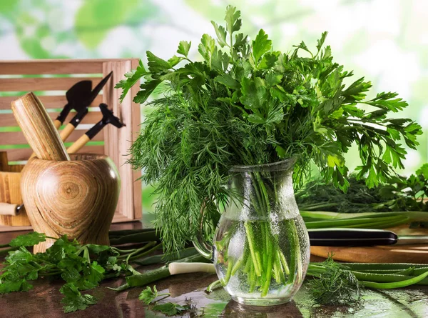 Bouquet di verdure fresche e bagnate in brocca, accanto a stupa di legno e cipolle in superficie — Foto Stock