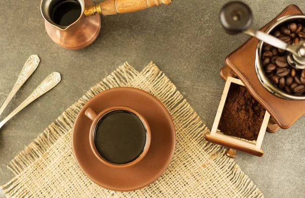 Granos de café, café molido y bebida en taza, en superficie gris — Foto de Stock