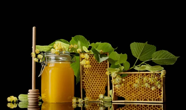 Panela com mel, quadro de madeira com favo de mel isolado em preto — Fotografia de Stock