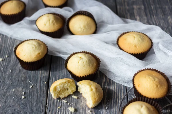 Grande número de cupcakes recém-assados e tecido branco na superfície de madeira cinza — Fotografia de Stock