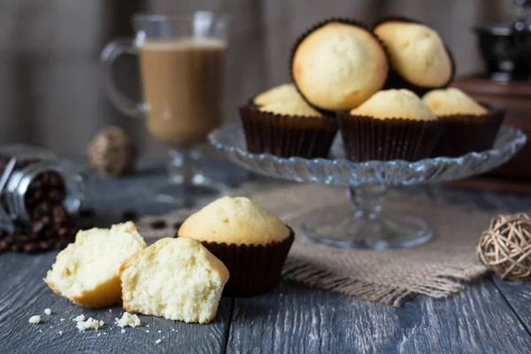 Cupcakes on glass dish, next to broken cupcake, on gray surface — Stock Photo, Image