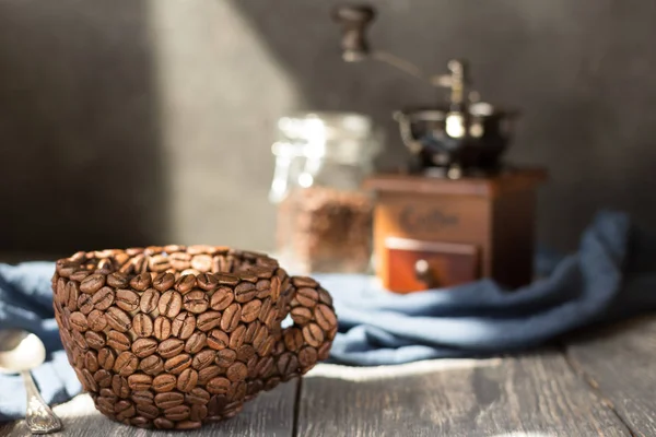 コーヒー豆で作られたカップ、灰色の木製のテーブルの上に立つ — ストック写真