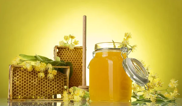 Molduras de madeira com favo de mel de cera e mel em jarra, no fundo amarelo — Fotografia de Stock