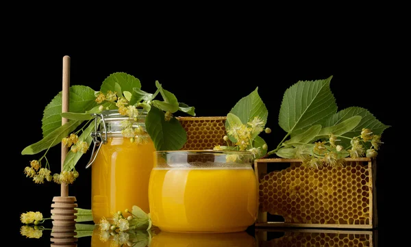 Frascos com mel, colher e favo de mel, isolados em preto — Fotografia de Stock