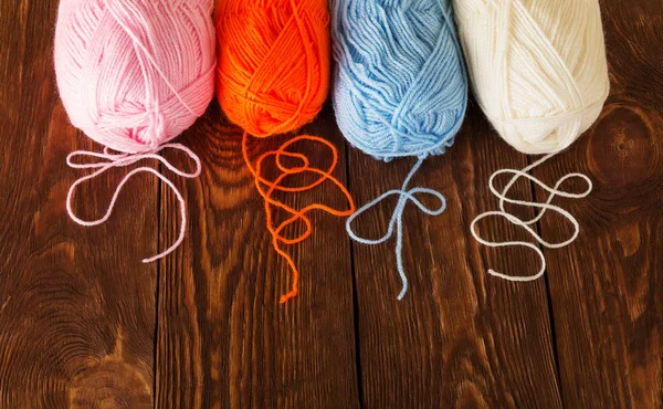 Skeins of yarn of different colors lie on wooden table — Stock Photo, Image