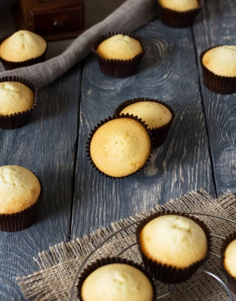 Lotes de deliciosos cupcakes em moldes na superfície de madeira — Fotografia de Stock