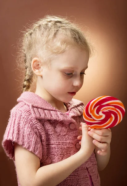 Маленькая кудрявая блондинка держит сладкие конфеты — стоковое фото