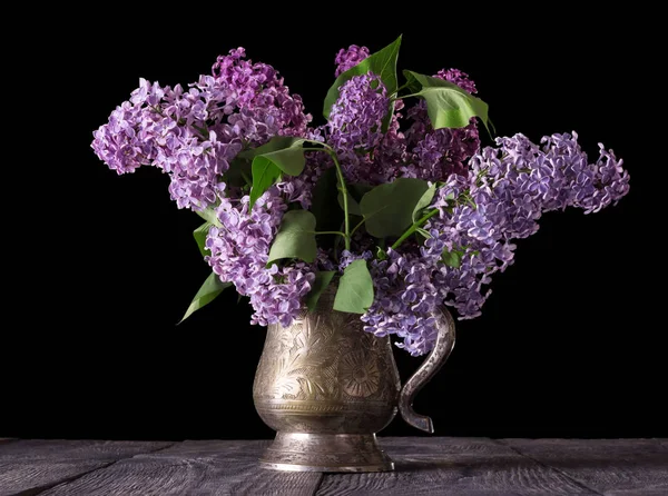 Bouquet of lilac in an old vase isolated on black background — 스톡 사진