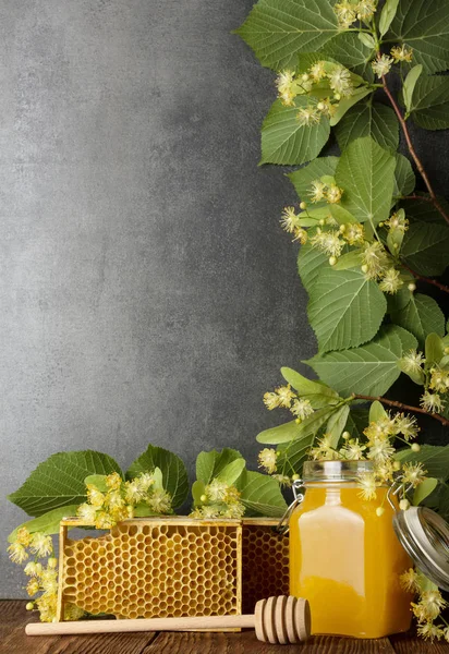 Ramo de linden de floração e jarra de mel fresco em cinza — Fotografia de Stock