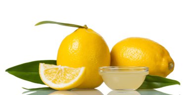 Yapraklı iki büyük limon, beyaz tencereye izole edilmiş limon suyu.
