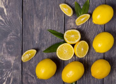 Gri yüzeyde bir sürü büyük sarı limon ve parça var.