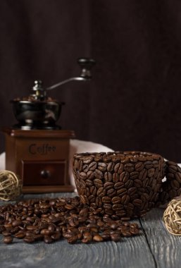 Kahve çekirdeğinden yapılmış fincan, saçılmış tahıl kahvesi, siyah üzerine izole edilmiş.