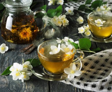 Çaydanlıkta sıcak yasemin çayı ve kaşıkların yanında fincanlar.