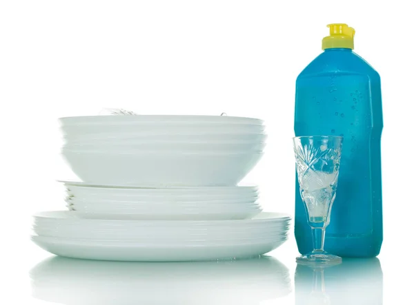 Стек чистих тарілок і кришталевих окулярів, пляшка з миючим засобом ізольована на білому — стокове фото