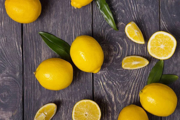 Grandes limones y piezas amarillas están dispersas en la superficie de madera — Foto de Stock
