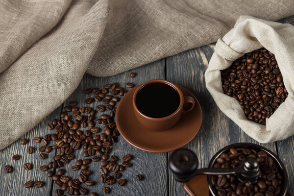 Lots of coffee beans, Cup with drink, hand mill, on gray background