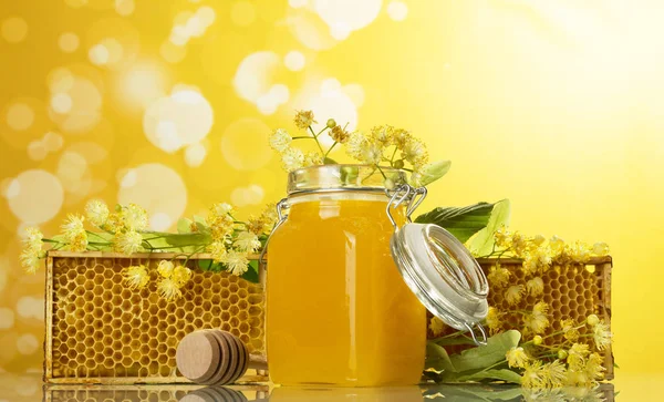 Molduras de madeira com favos de mel e jarra de mel no fundo amarelo — Fotografia de Stock