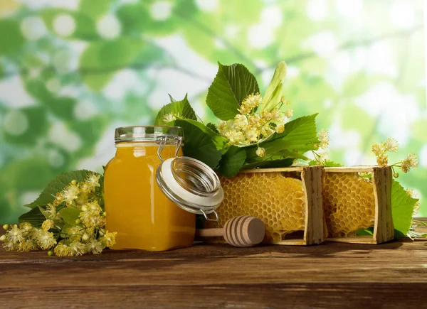 Mel de maio em jarra, favo de mel de cera em armação e flores perfumadas em mesa de madeira — Fotografia de Stock