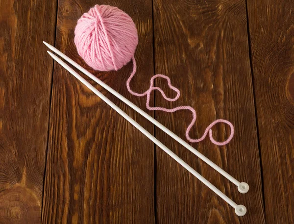 Skein of soft pink yarn and knitting needles on wooden surface — Stock Photo, Image
