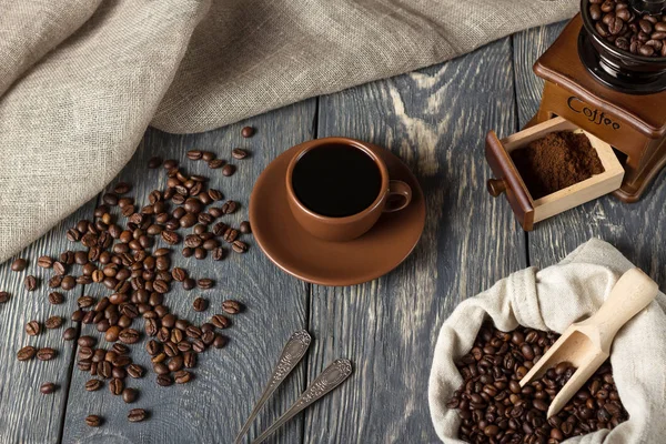 Coffee beans, ground coffee and hot drink in a Cup, on wooden surface