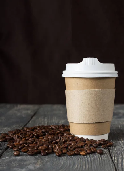 Coppa una tantum con bevanda e chicchi di caffè sparsi, su nero — Foto Stock