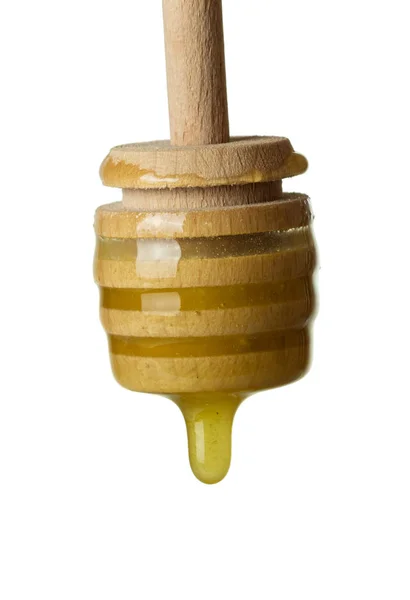 Fuso de madeira e mel pingando, isolado em branco — Fotografia de Stock