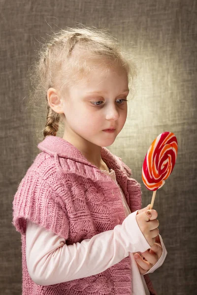 Маленькая девочка внимательно смотрит на конфеты, на серые — стоковое фото