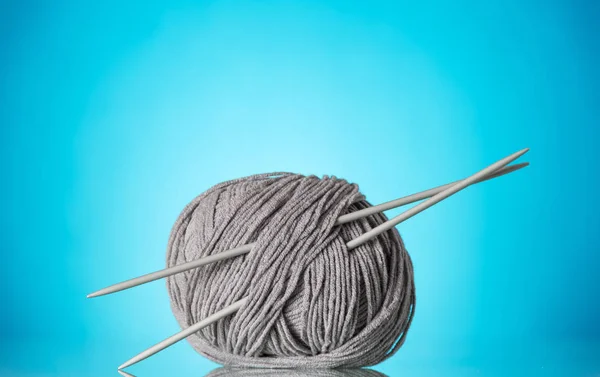 Skein of thick, grey yarn and knitting needles on blue — Stock Photo, Image