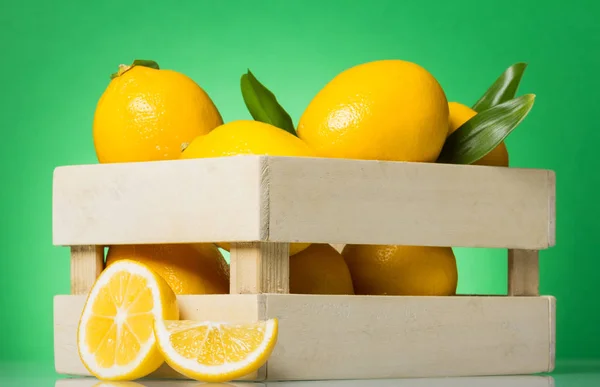 Zitronenschachtel, in der Nähe der Schnittfrüchte, auf grün — Stockfoto
