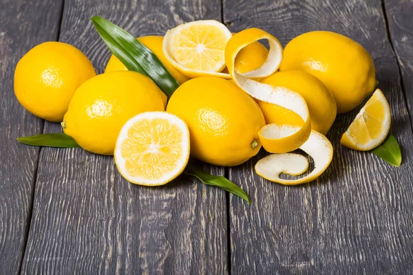 Leuchtend gelbe Zitronen und geschälte Schale, auf grauer Oberfläche — Stockfoto