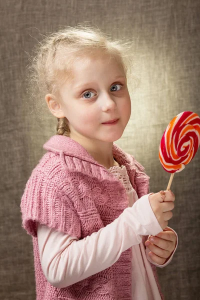 Очаровательная блондинка с кольцом на пальце, держащая конфеты на палочке — стоковое фото