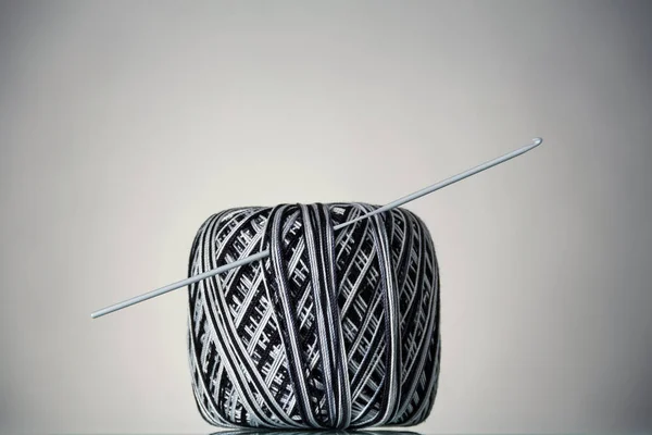 Hank of black and white yarn and crochet hook, on grey — Stock Photo, Image