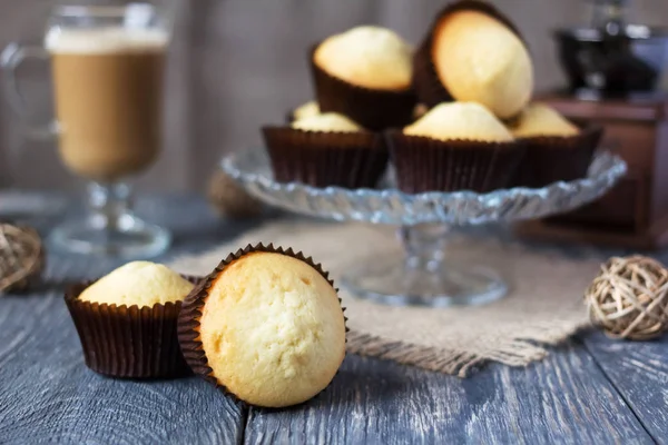 Glissière de cupcakes en support de verre, près de cupcakes en moules, sur table grise — Photo