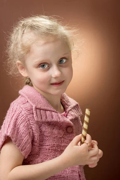 Charming blonde girl smiles, holds sweets in hand — Stock Photo, Image