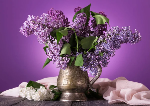 Lilac flowers in an old vase, near sprig of white flowers on background of fine fabric — Stock Photo, Image