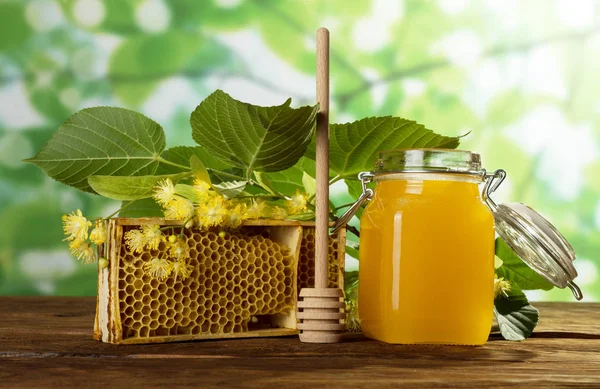 Frasco cheio de mel de maio, favos de mel de abelha e raminho de Linden, colher na mesa — Fotografia de Stock