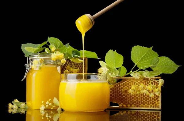 Due vasetti di vetro con miele, cornici con celle d'api, fuso con miele, isolati su nero — Foto Stock
