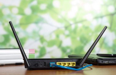 İnternet kablosu yönlendiriciye bağlı, masadaki modern iletişim cihazlarının yanında.