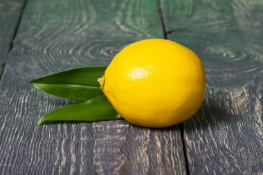 Ahşap masada yeşil yapraklı parlak sarı limon.