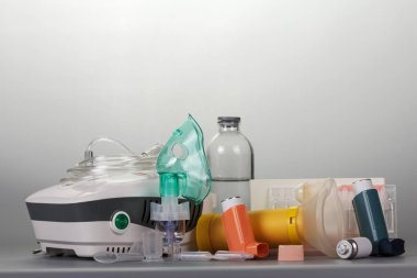 Compressor and portable inhalers, replaceable dispenser, ampoules and baby mask, on grey